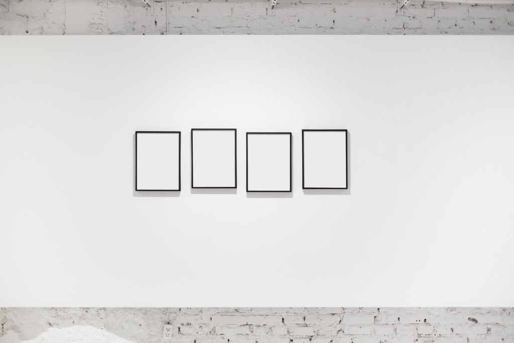 A white wall with four empty photo frames