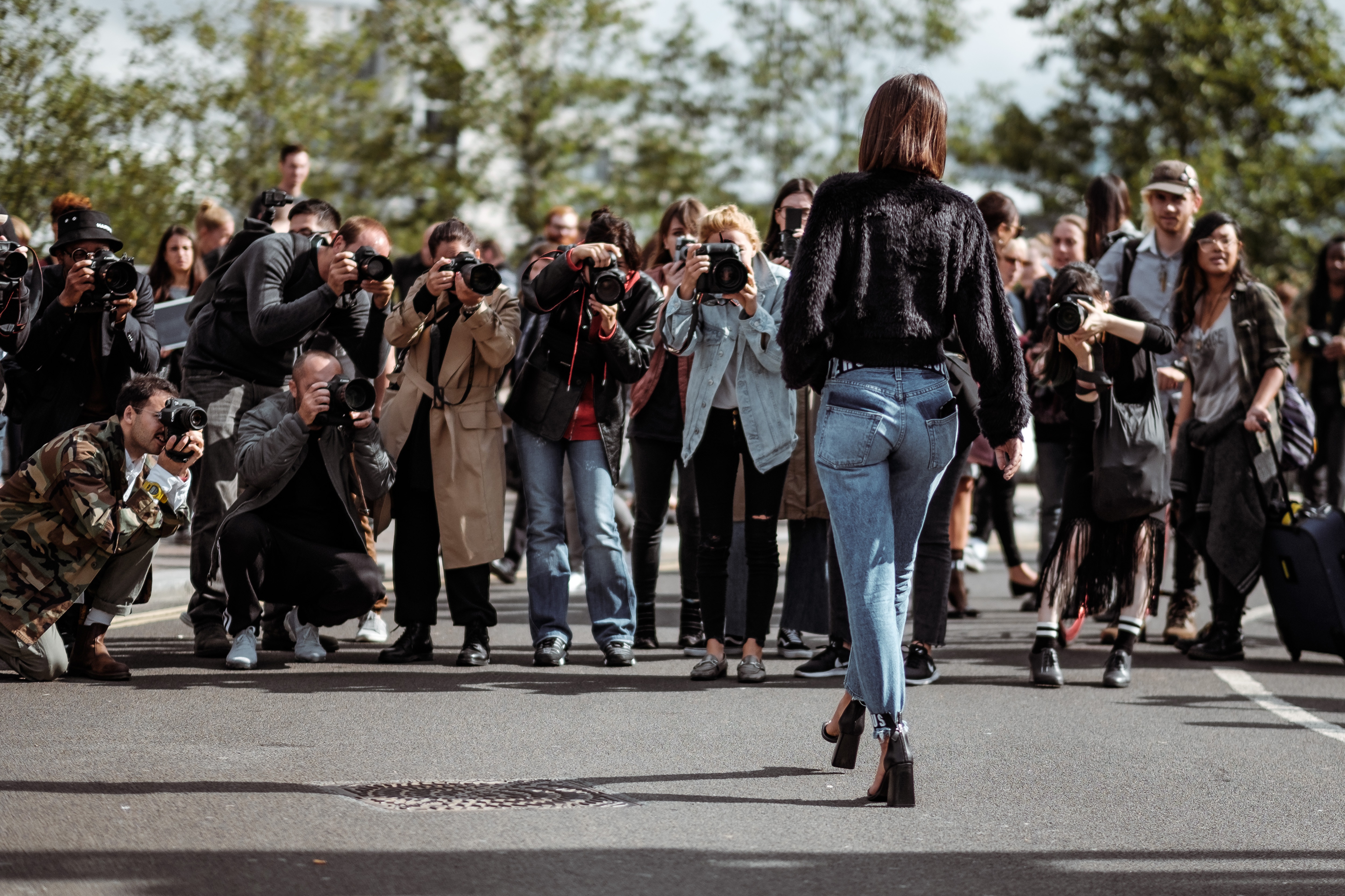 Mainstream influencer is photographed by paparazzi. 