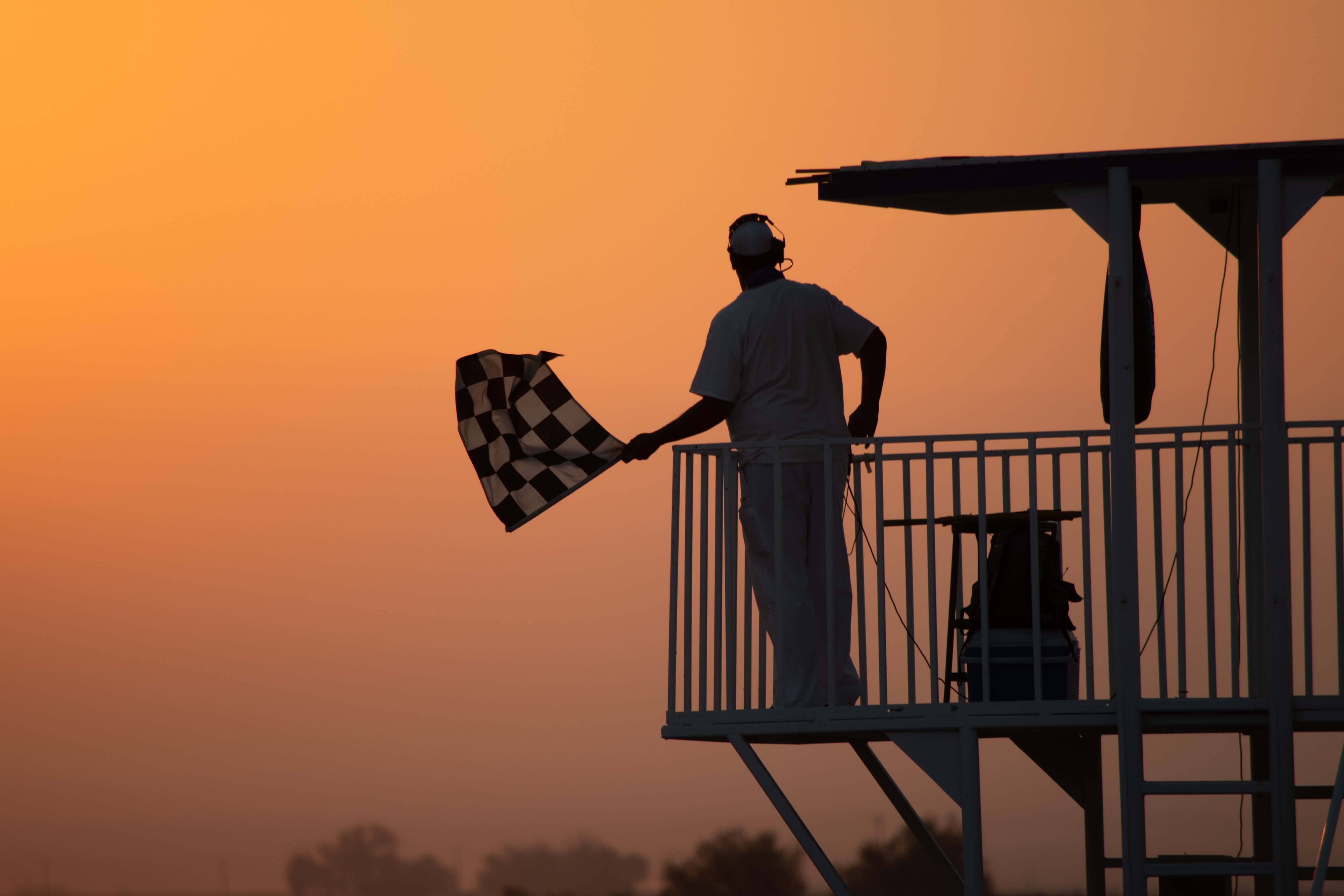 sales and marketing - a man waves a chequered flag at sunset
