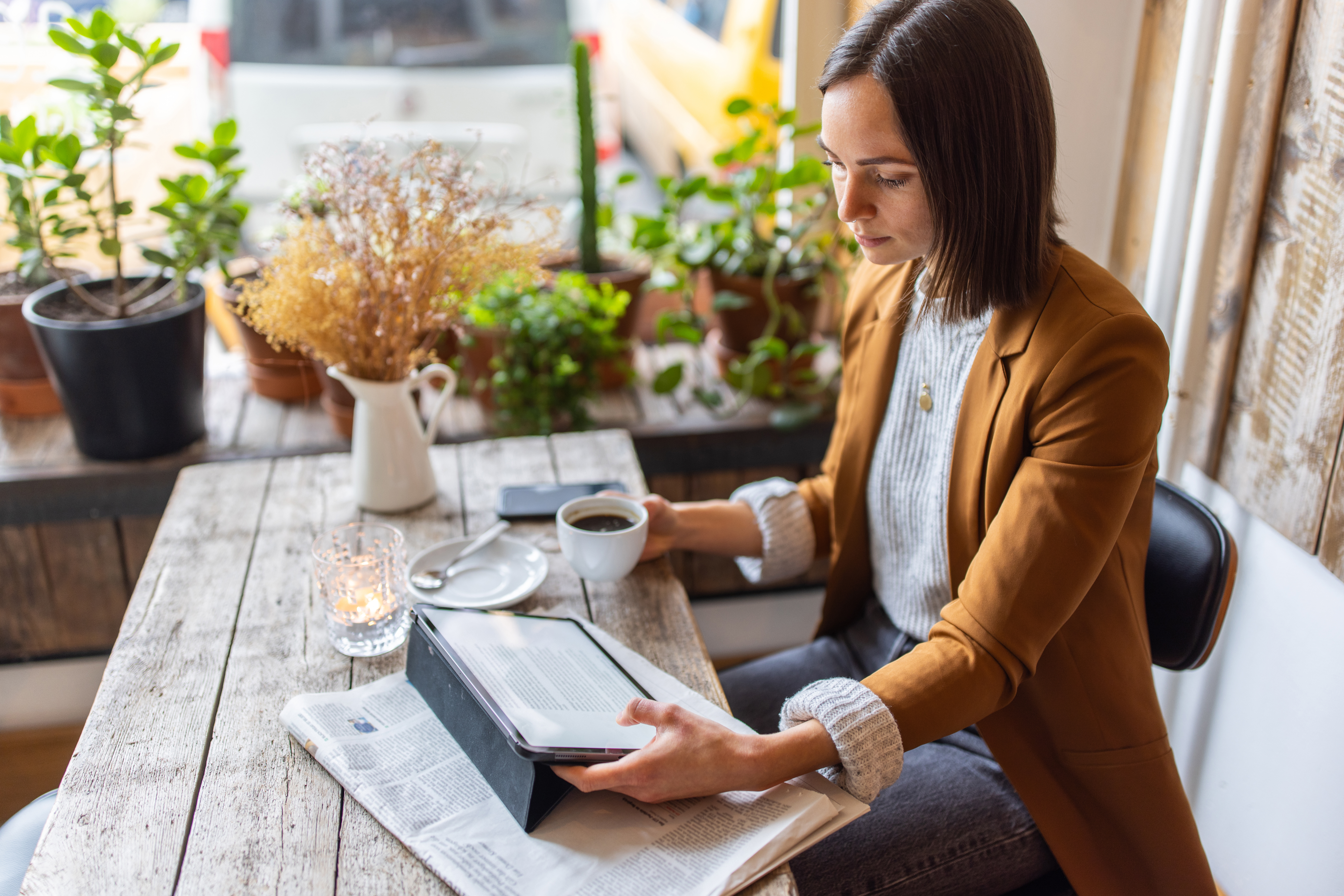 Businesswoman sitting at a coffee shop using digital tablet. Female having coffee and working on a tablet pc sitting at a cafe.