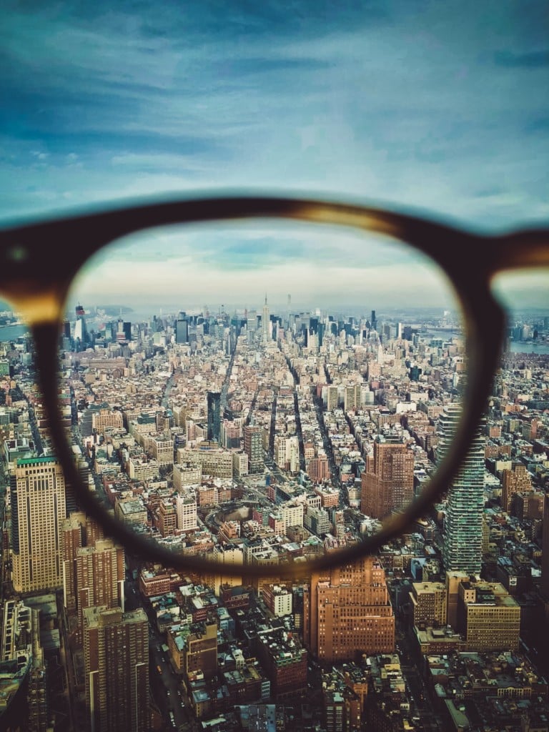 A cityscape shown through one lens of a pair of glasses