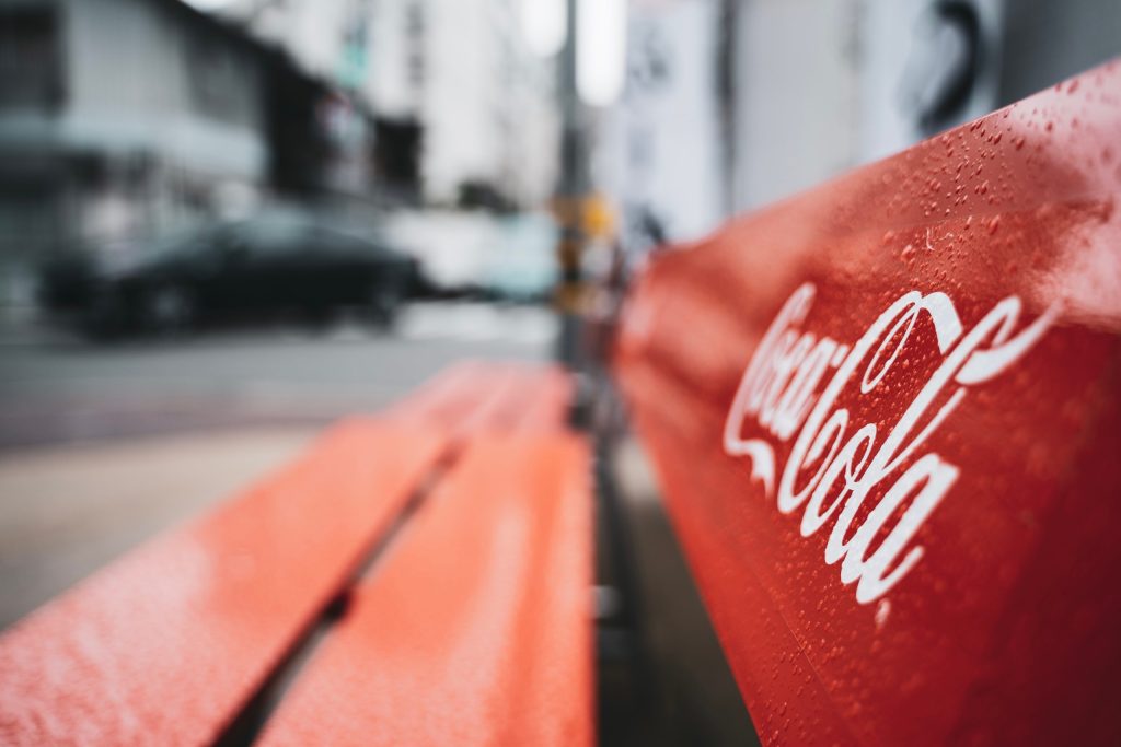 A photo of a bench branded with Coca Cola in a rainy street