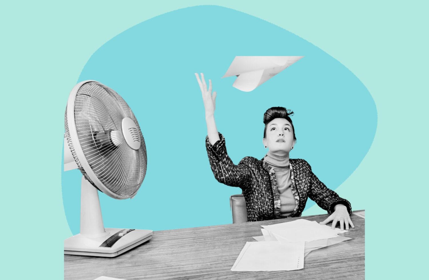 woman at desk throwing paper in air