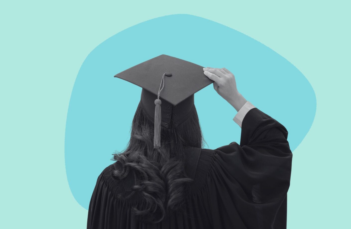 Woman wearing graduation garments with her hand holding the cap